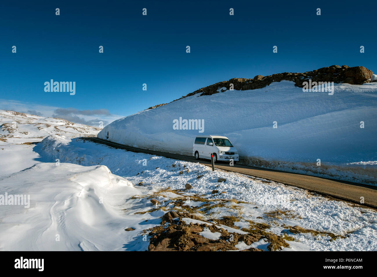 Una Mazda Bongo campervan passando un grande snow drift in prossimità del vertice dell'Bealach na Bà road, nelle colline Applecross, regione delle Highlands, Scotland, Regno Unito Foto Stock