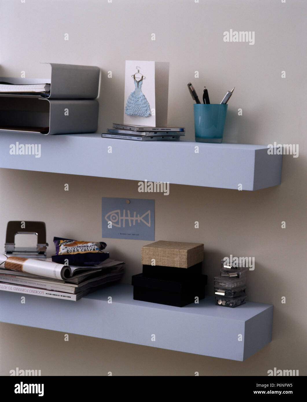File di metallo vassoi e attrezzature di cancelleria su semplice blu pallido scaffalatura Foto Stock