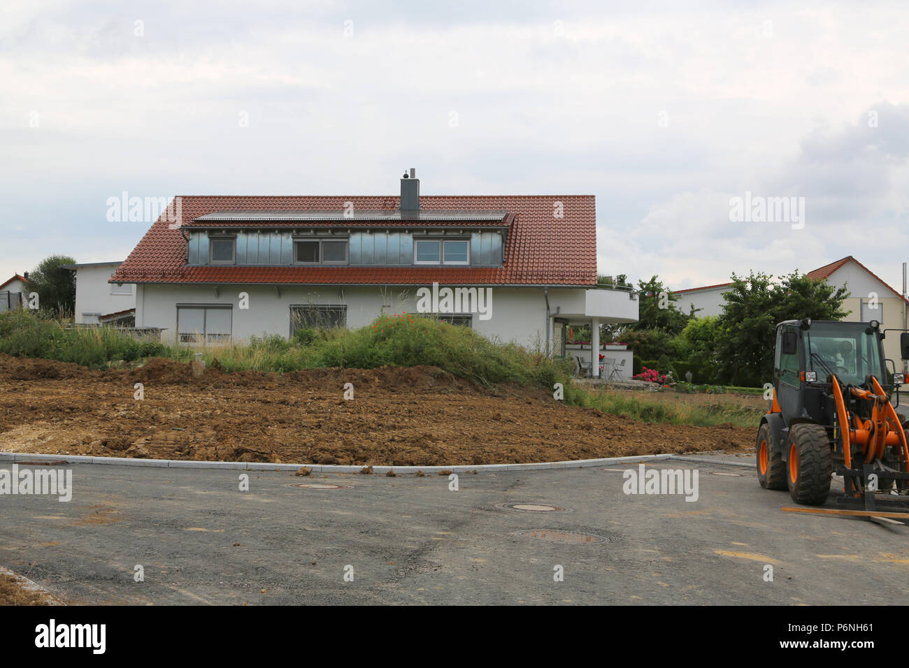 Una strada è stata costruita e utilità di linea sono state stabilite per la costruzione di una nuova comunità residenziale in Germania.Il trattore prepara il terreno per Foto Stock