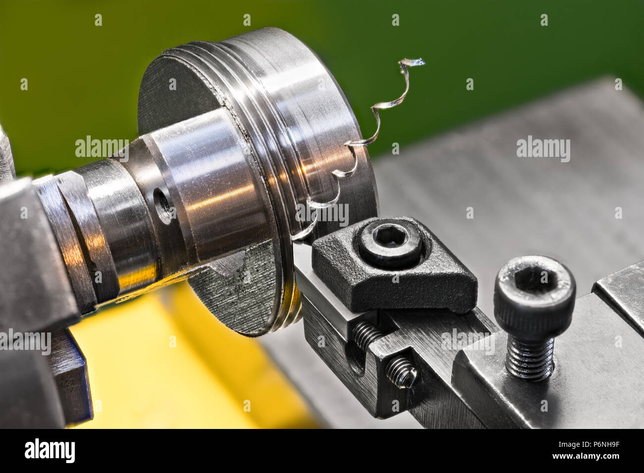 Filettatura per un utensile in acciaio bit su un tornio. Close-up di tornitura di un pezzo metallico serrato nelle ganasce del mandrino della macchina utensile. Bella la presenza di limatura di ferro ritorto. Foto Stock