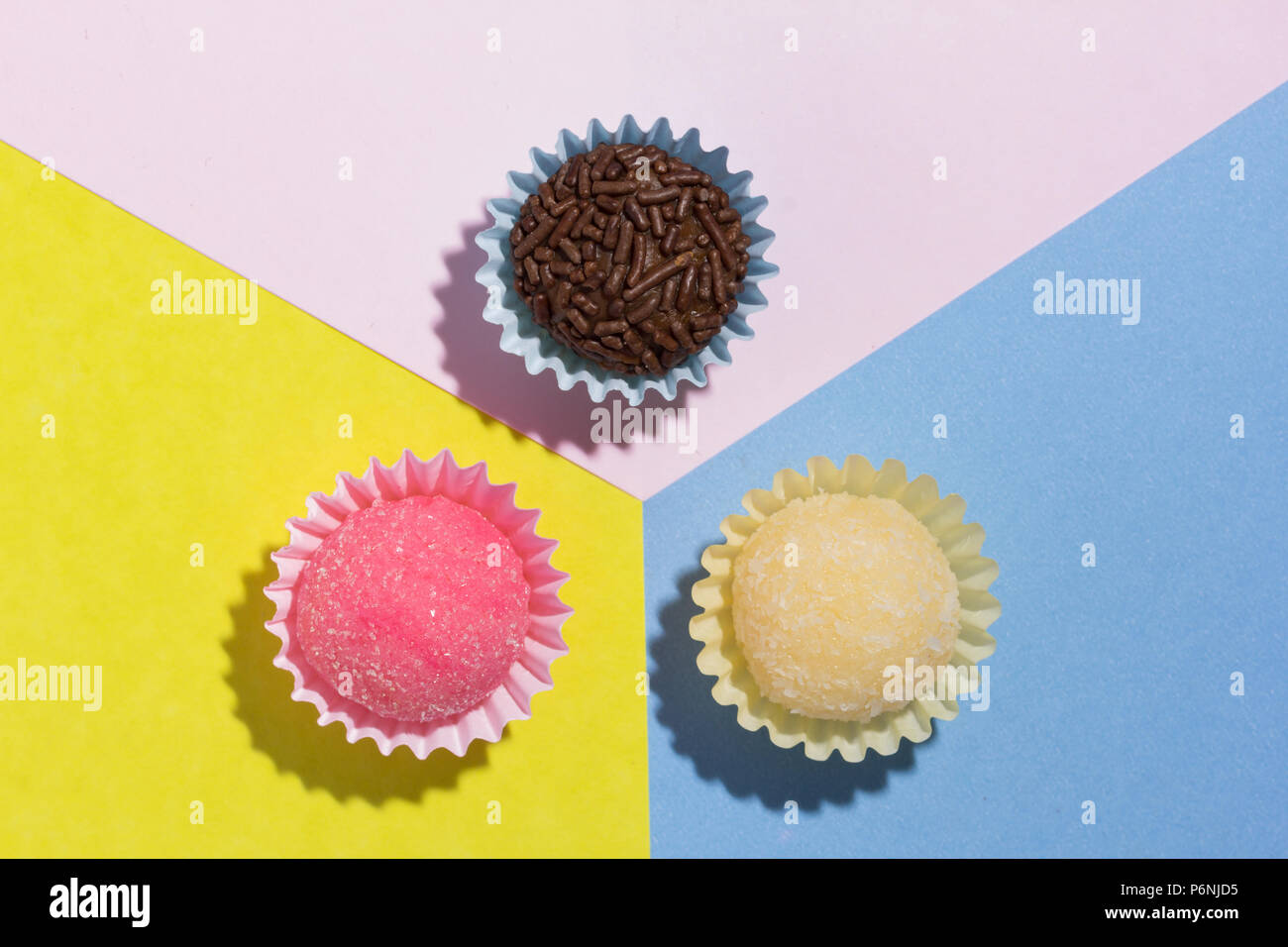 Caramelle brasiliano: Brigadeiro, Beijinho e Bicho de Pe. Bambini festa di compleanno. Design piatto di caramelle palla sul colore di sfondo. Foto Stock