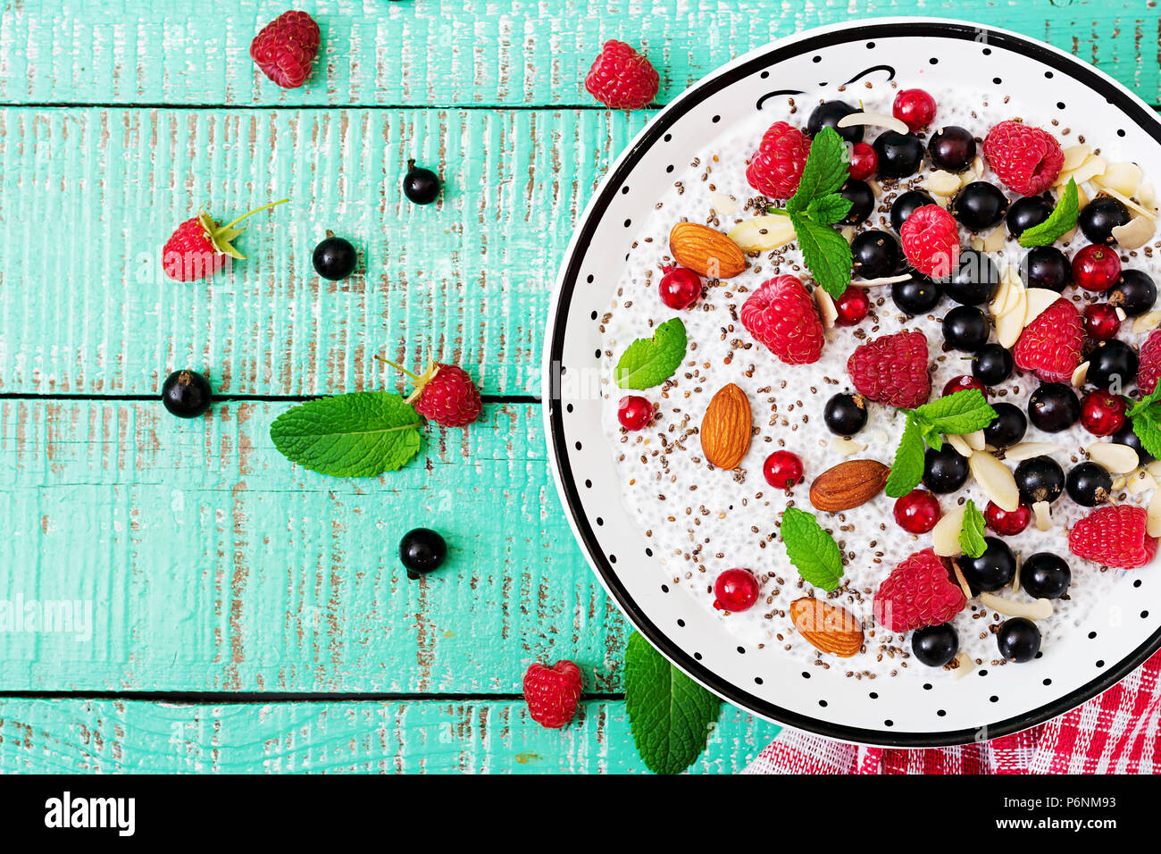 Detox e superfoods sana prima colazione nella ciotola. Vegan latte di mandorla chia semi pudding con lamponi, more e menta. Vista dall'alto. Lay piatto Foto Stock