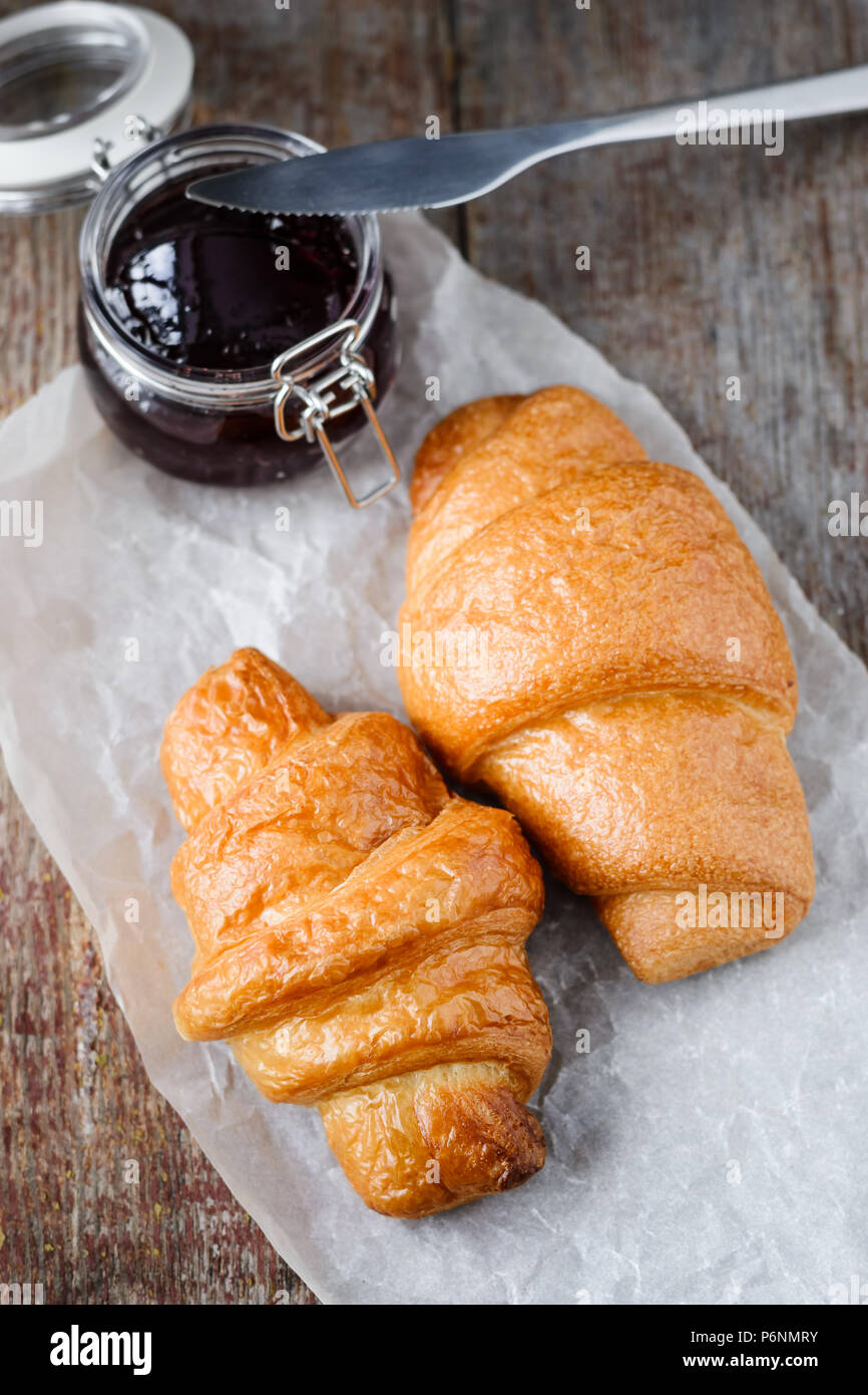 Due appetitosi croissant freschi e marmellata sul tavolo di legno Foto Stock