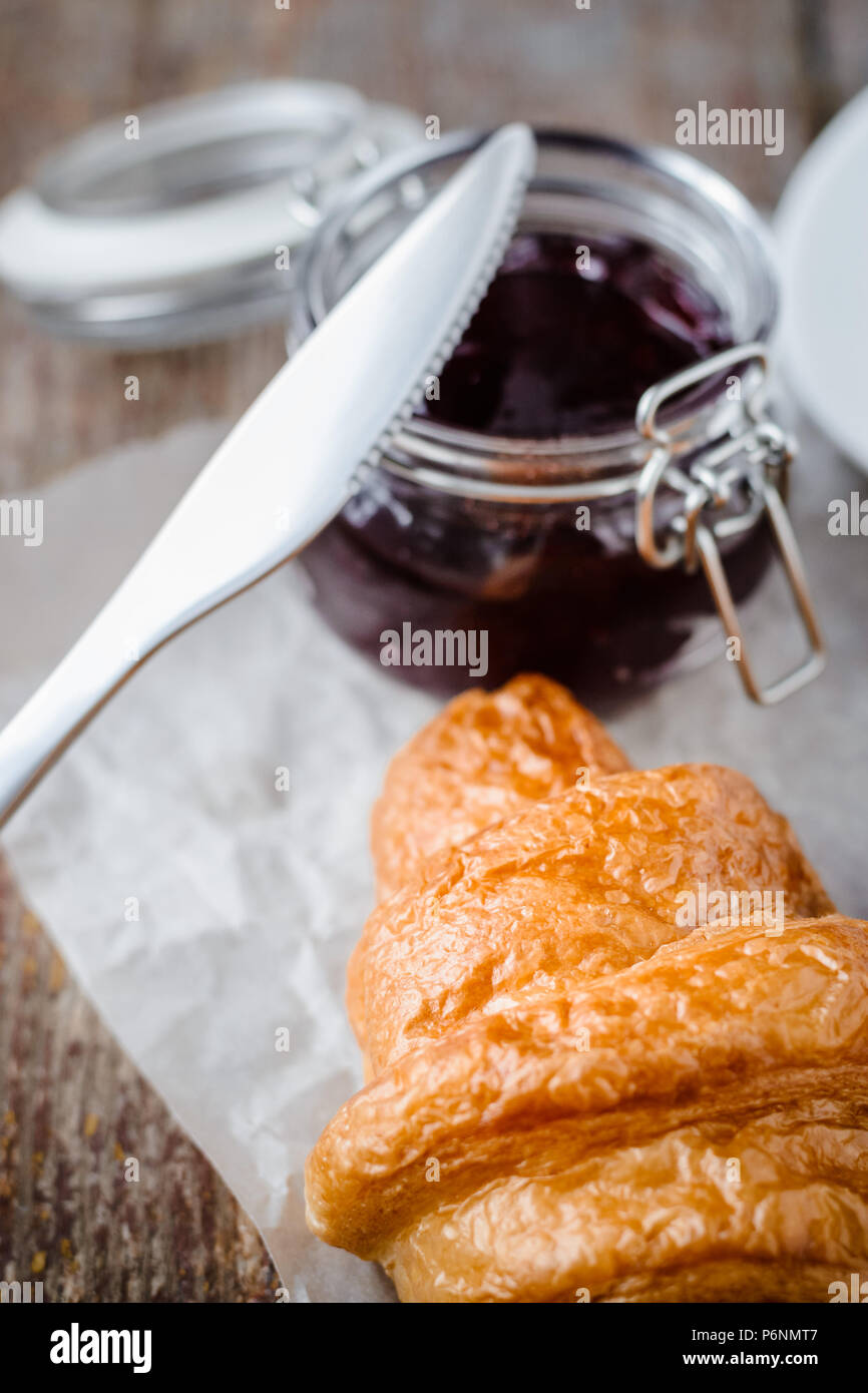 Cornetto marmellata in un recipiente su un tavolo di legno. Colazione veloce Foto Stock
