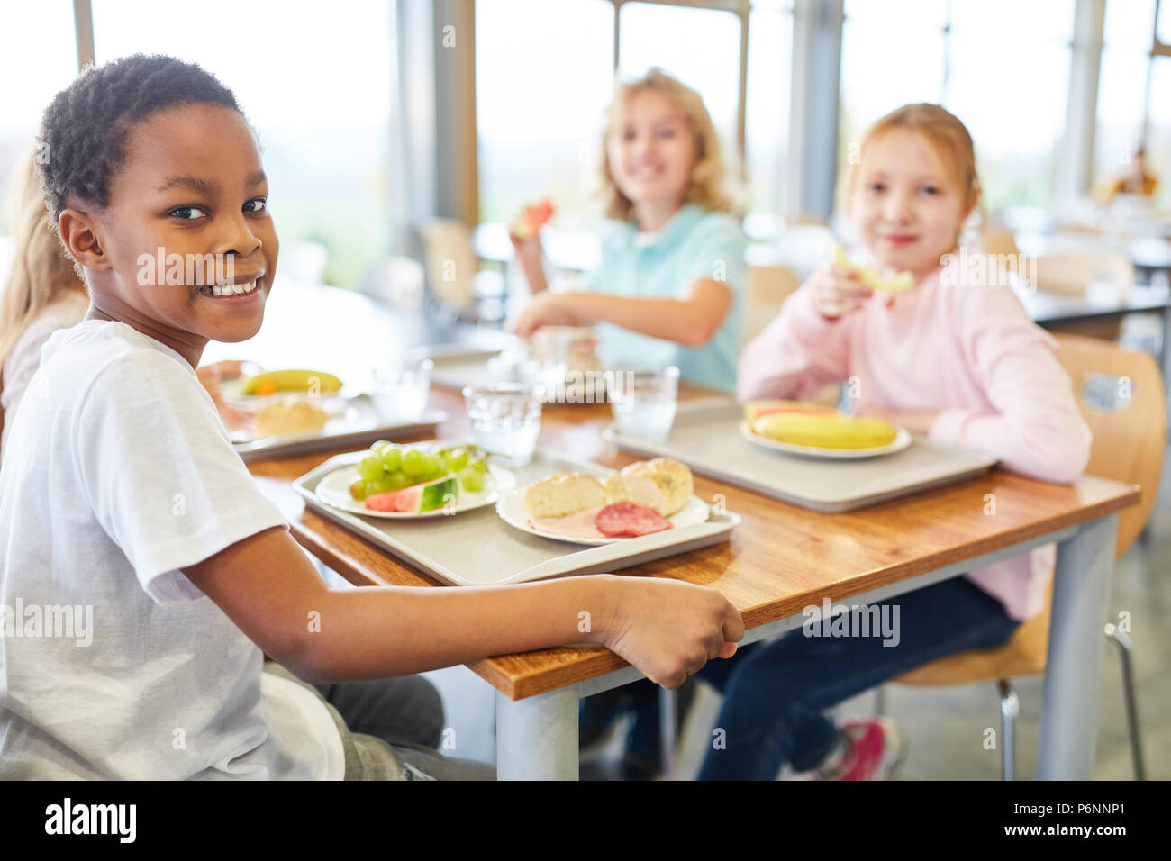 I bambini mangiano insieme nella mensa del multiculturale della scuola elementare Foto Stock