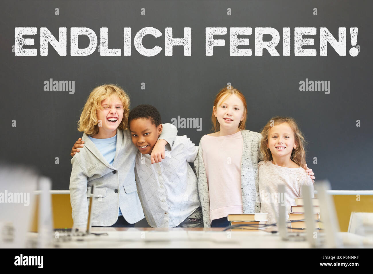 Felice gruppo di bambini è in piedi di fronte a una lavagna con il tedesco slogan 'Endlich Ferien' (vacanze finalmente!) Foto Stock