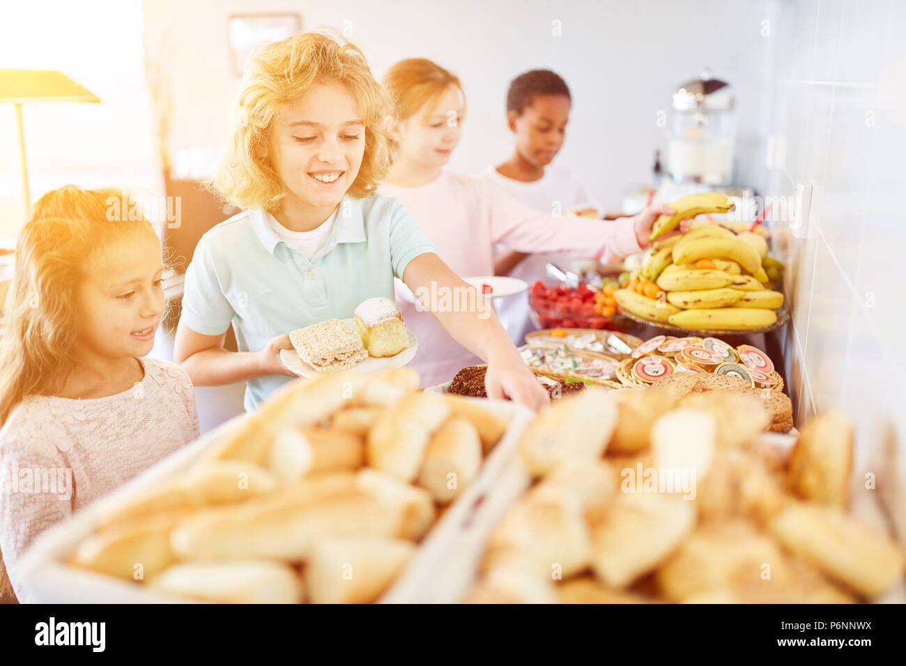 Dei bambini felici di portare cibo al buffet di una mensa a scuola Foto Stock