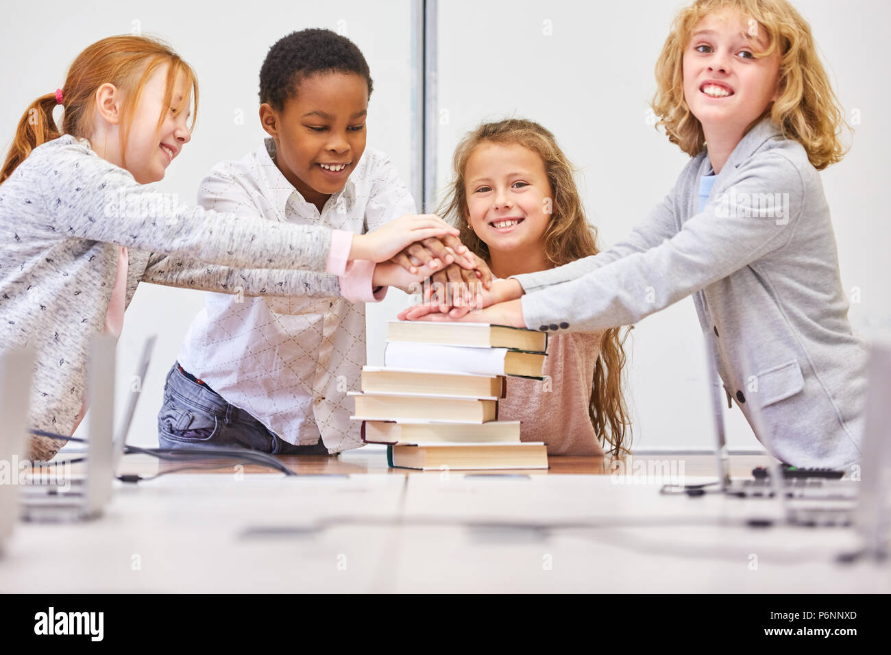 Glückliche Schüler in Grundschule stapeln die Hände auf Büchern zur motivazione Foto Stock