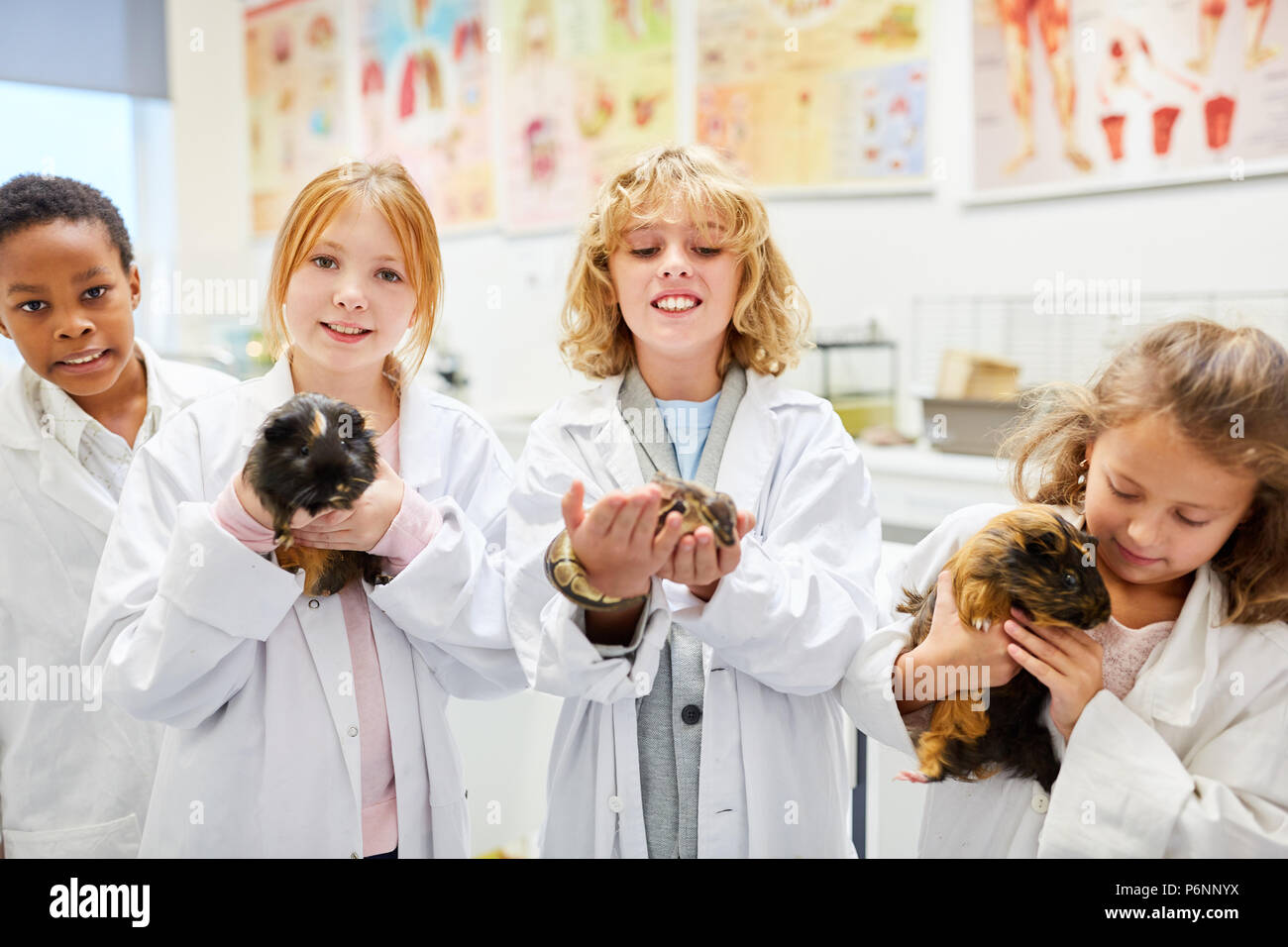 Un gruppo di bambini della scuola elementare con diversi animali nella lezione di biologia Foto Stock