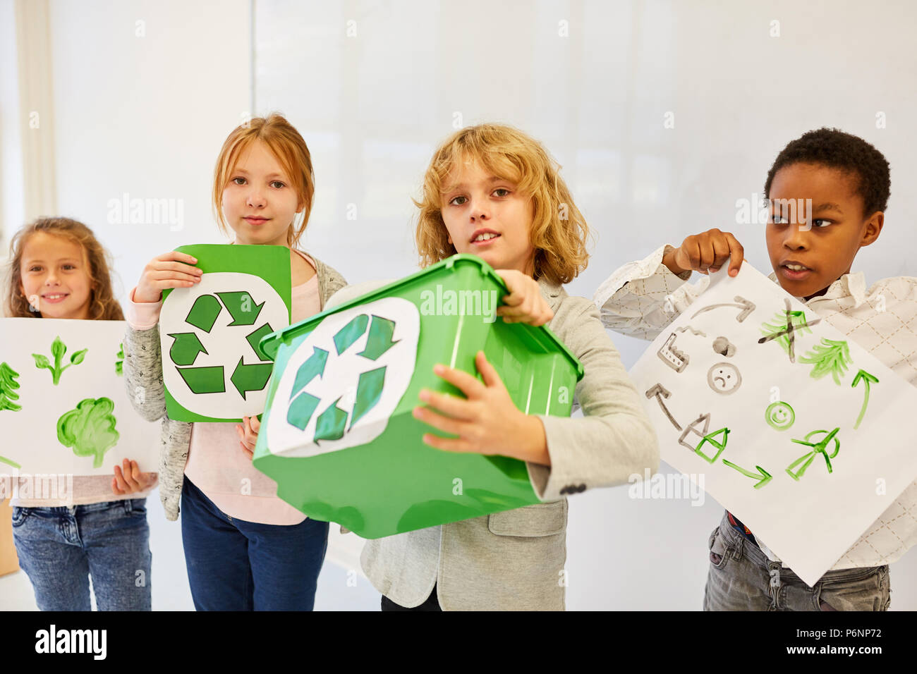 Gli studenti della scuola elementare di mantenere i disegni per ambientale progetto di riciclaggio Foto Stock