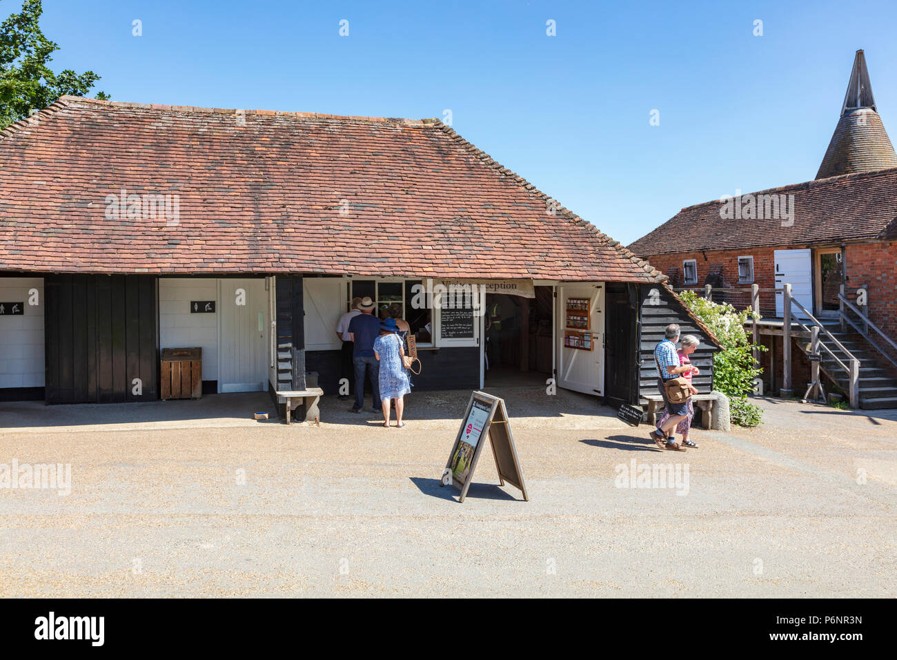 I visitatori che arrivano presso il castello di Sissinghurst Gardens su una intensa giornata d'estate. Preso da un pubblico Bridleway, Kent, Regno Unito Foto Stock