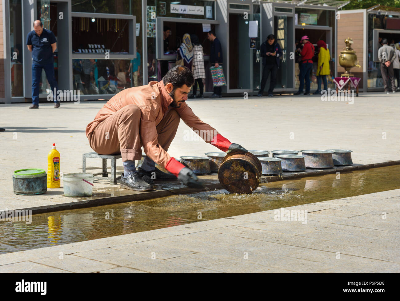 Khorramabad, Lorestan Provincia, Iran - 31 Marzo 2018: iraniano che lava utensili in ferro in creek nella piazza centrale della città Foto Stock