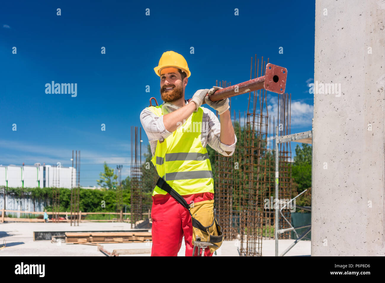 Colletto blu lavoratore portando una pesante barra metallica durante il lavoro Foto Stock