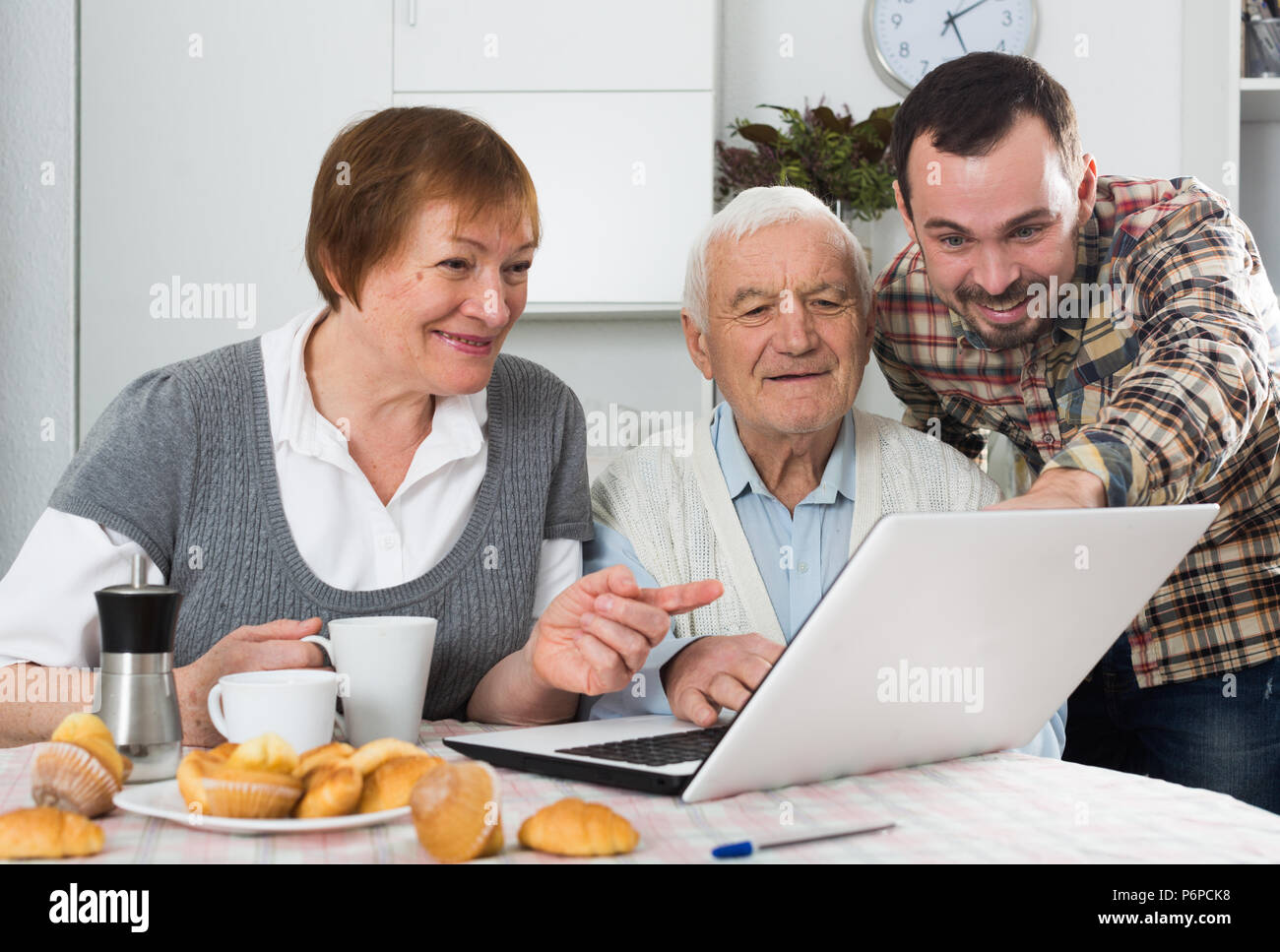 Famiglia sorridente guardando interessanti notizie e video su Internet su notebook a casa Foto Stock