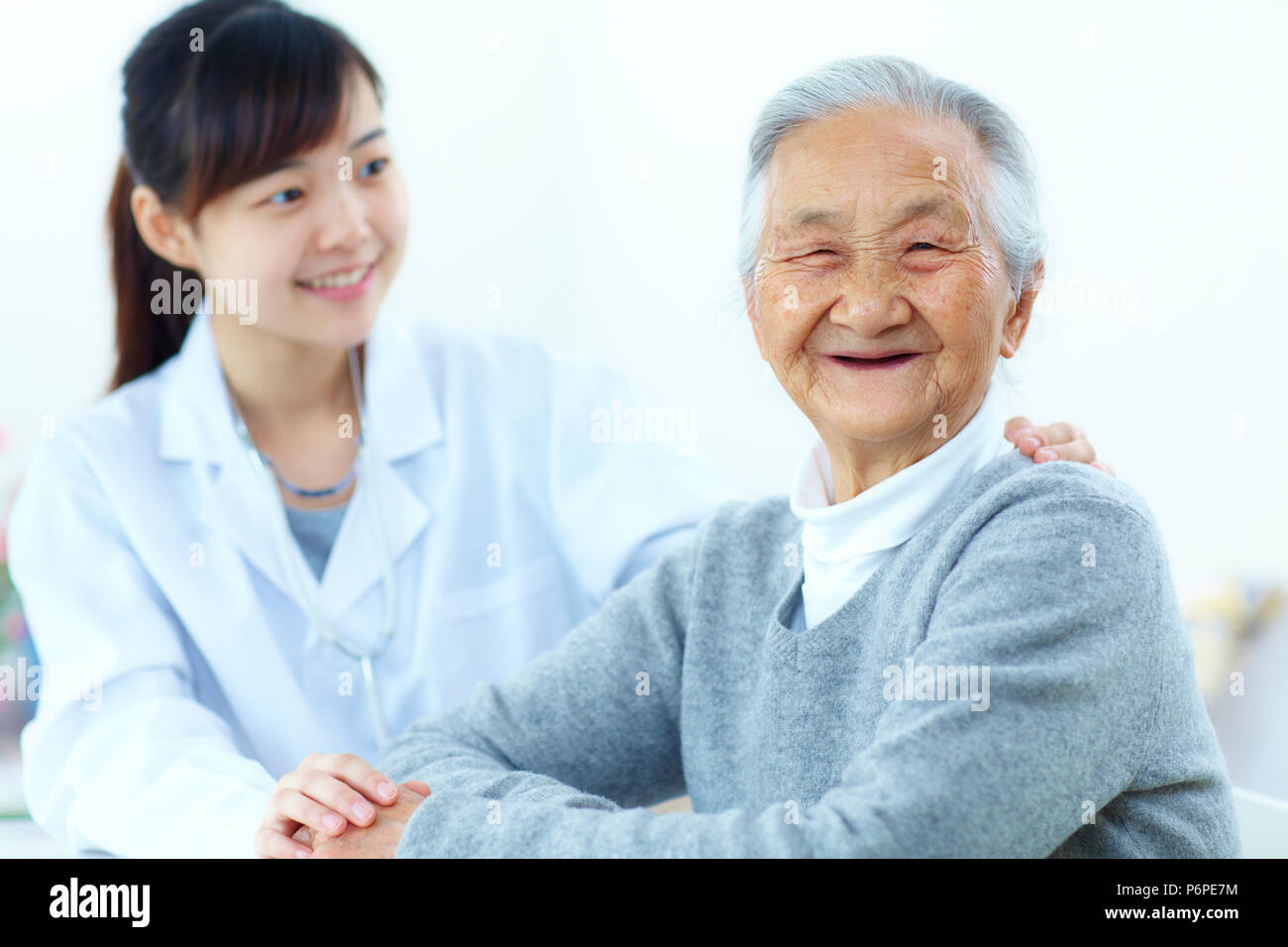 Una giovane donna asiatica medico facendo health check per senior donna cinese, personale senior health care Foto Stock