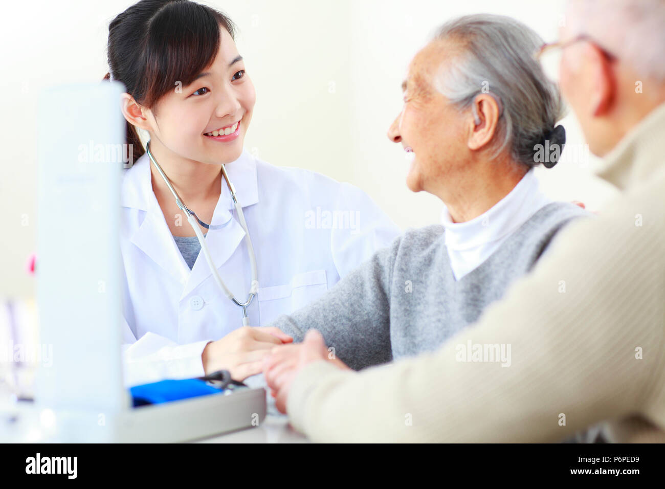 Una giovane donna asiatica medico facendo health check per senior donna cinese, personale senior health care Foto Stock