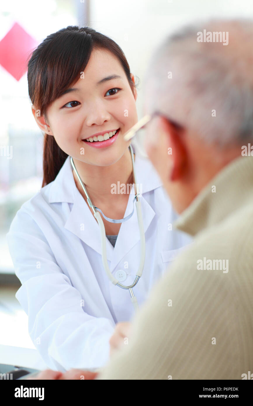 Giovani asiatici medico donna facendo medico di controllo sani ai senior uomo cinese Foto Stock