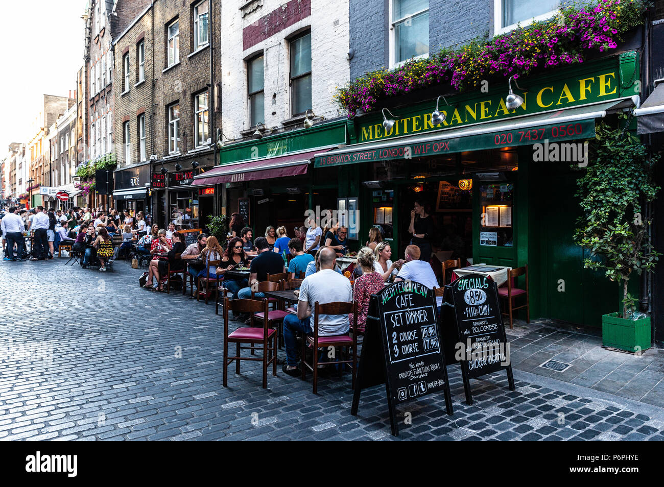 Fila di ristoranti dove i clienti possono mangiare fuori in strada a ciottoli, Berwick Street, Soho, Londra, Inghilterra, Regno Unito. Foto Stock