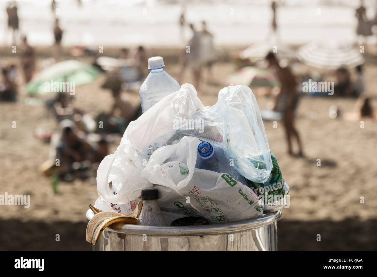 Cucciolata traboccante di scomparto pieno di bottiglie di plastica e sacchetti di plastica sulla spiaggia Foto Stock