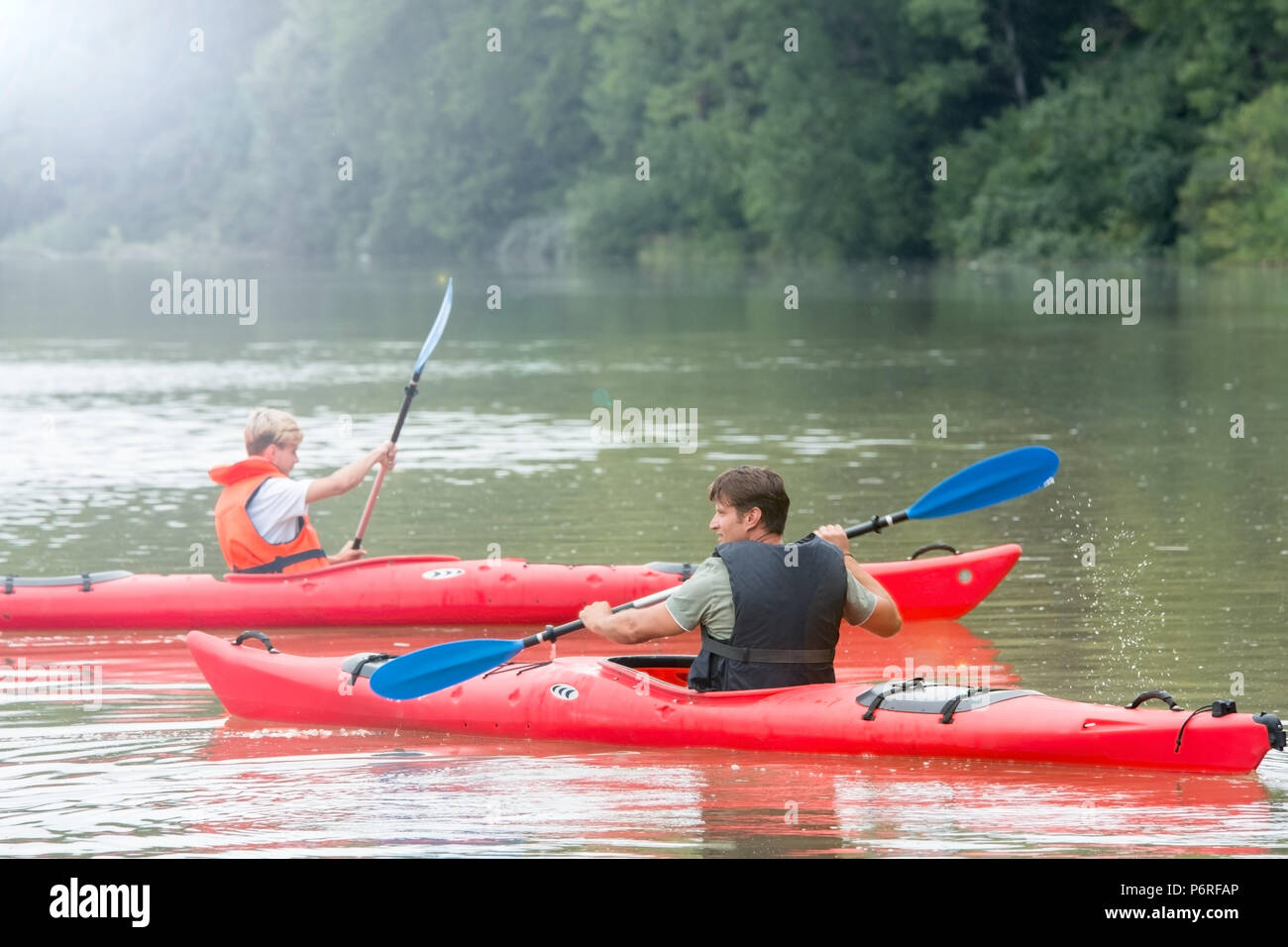 Padre e figlio, ciascuna pala una canoa sul lago di montagna Foto Stock
