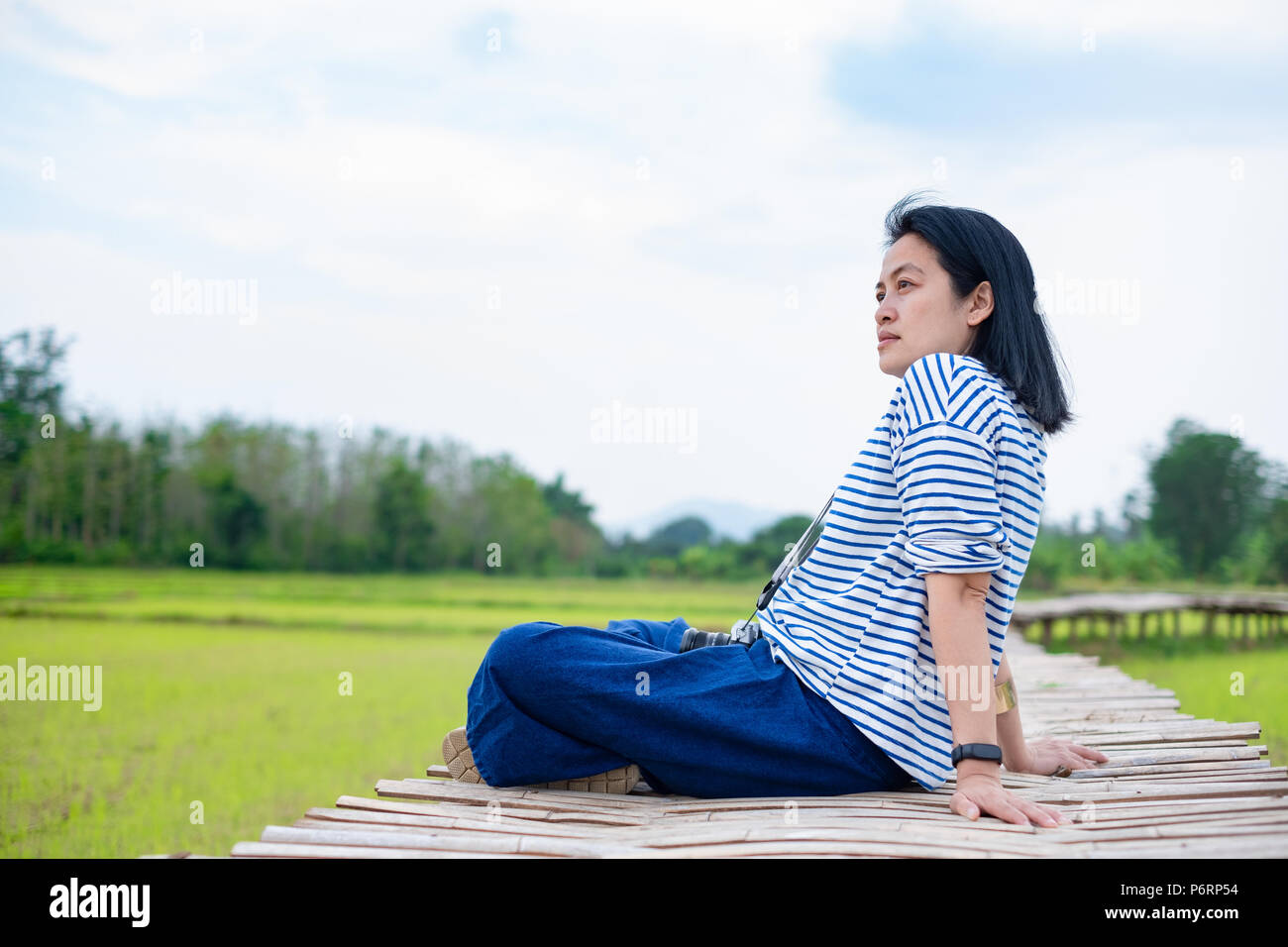 Donna asiatica seduta gamba trasversale sul ponte di bambù al campo di riso alla sera volta sentire rilassati e fresche con valve emotion.natural travel Foto Stock
