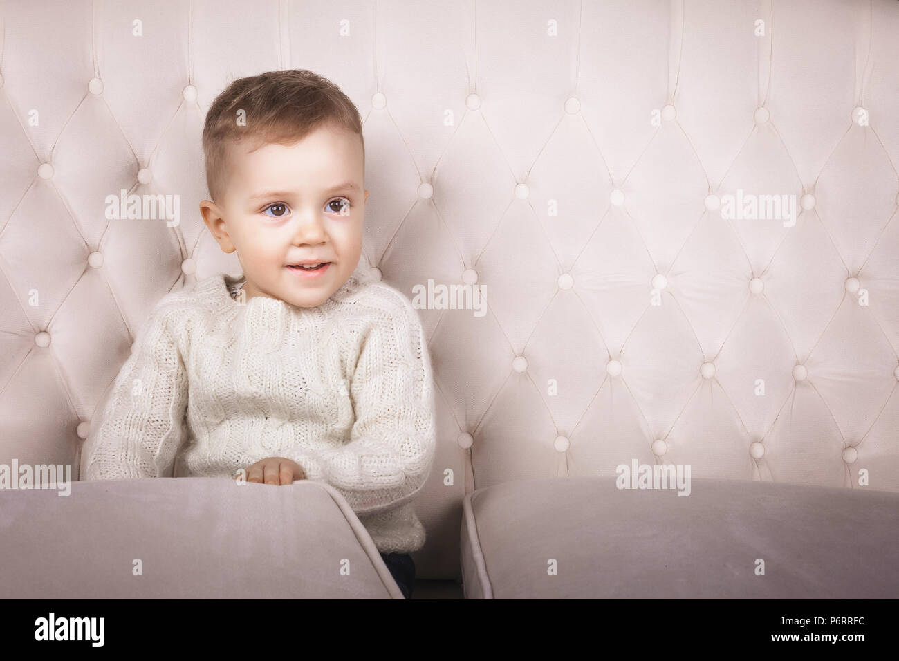 Bambino seduto sul divano elegante Foto Stock