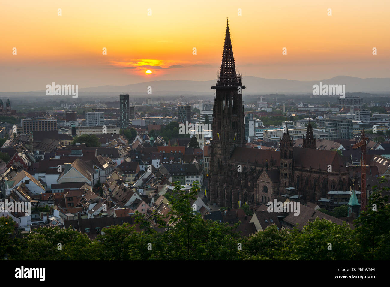 Germania, antica minster e case di Freiburg im Breisgau in arancione la luce del tramonto Foto Stock