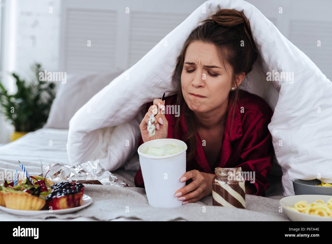 Donna di mangiare un sacco di dessert a causa della depressione Foto Stock