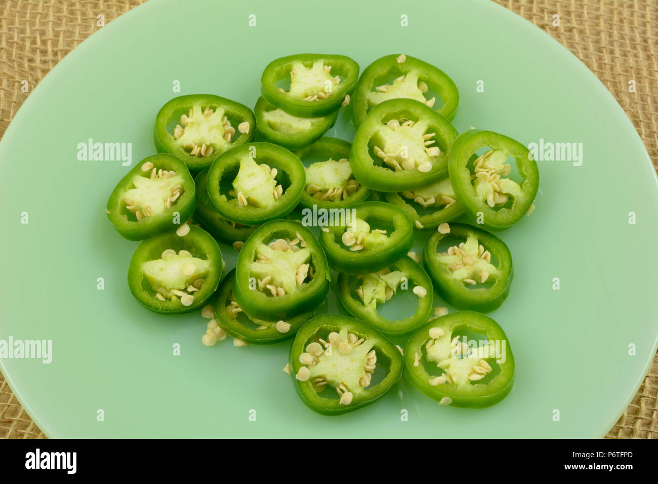 Materie affettato jalapeno anelli sulla piastra verde preparata come ingrediente di cottura o snack Foto Stock