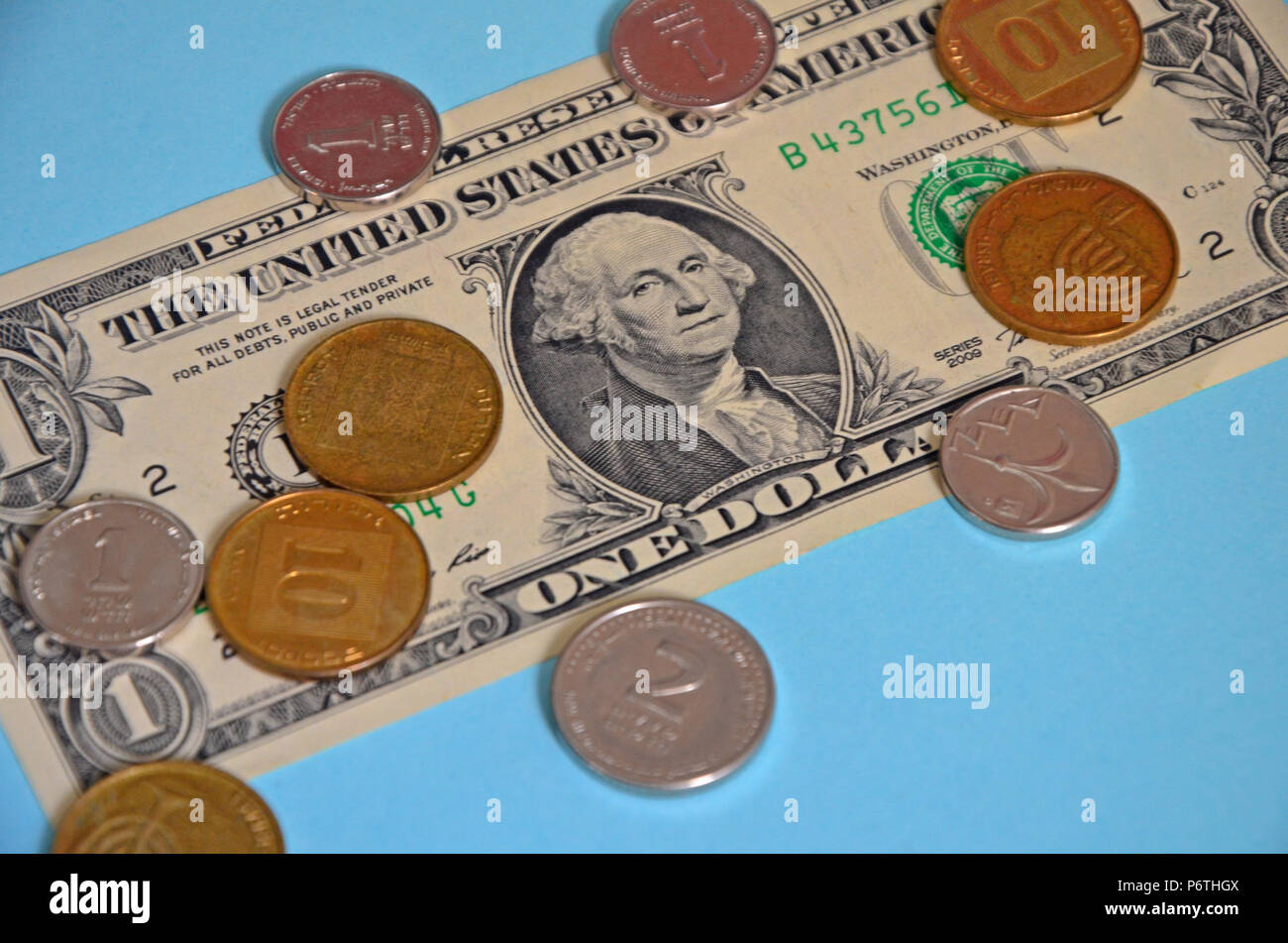 Monete metalliche 1 e 2 sheqel israeliano e 10 agorot giacciono su un dollaro statunitense. Una carta delle banconote e delle monete su uno sfondo blu. Foto Stock