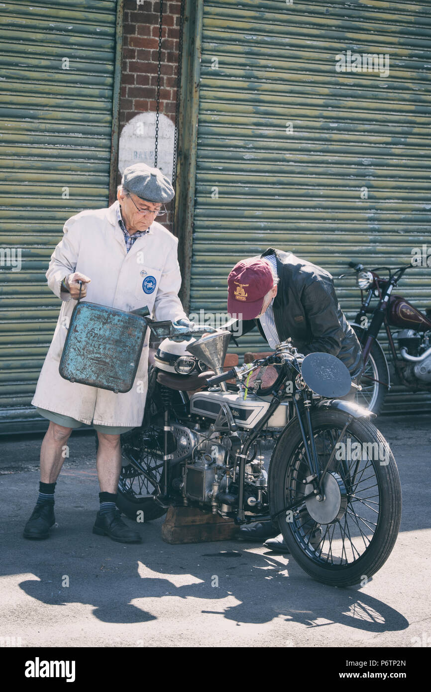 Gli uomini il rifornimento di carburante a 1928 Douglas SW5 Velocità modello di motocicletta a Bicester Heritage Centre festival volano, Oxfordshire, Inghilterra. Vintage filtro applicato Foto Stock