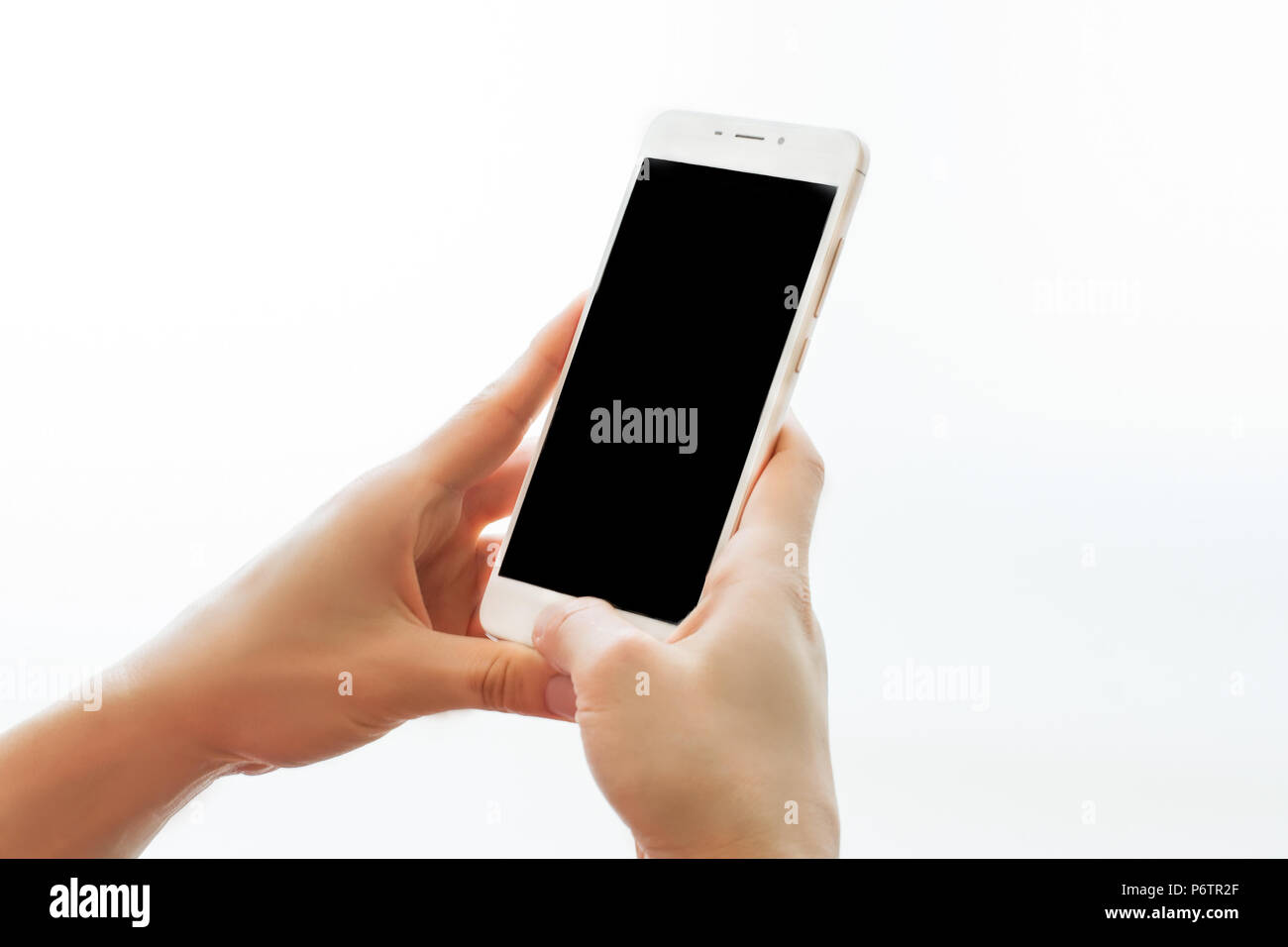 Mani femminili holding smartphone con schermo nero isolato su sfondo bianco. Il dispositivo mobile vicino. Mock up concept Foto Stock