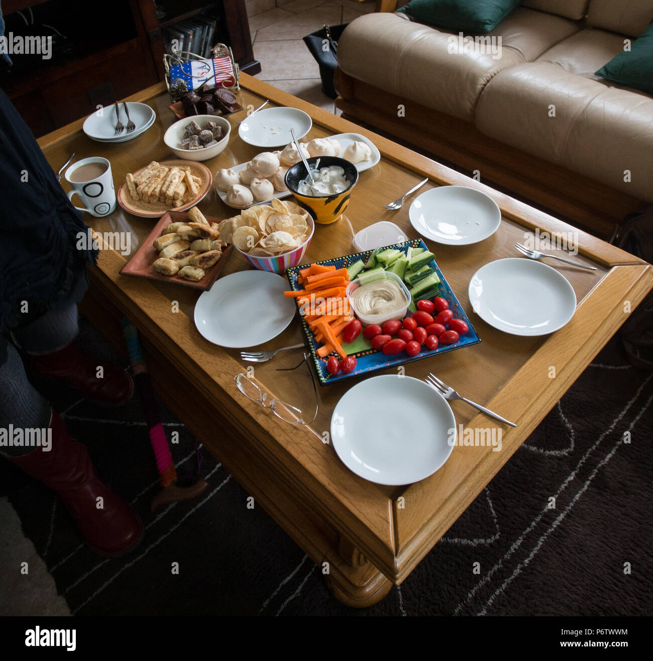 varietà di stuzzichini dolci e salati o spuntini su un tavolino da caffè in un salotto di casa preparato per un tè pomeridiano informale Foto Stock