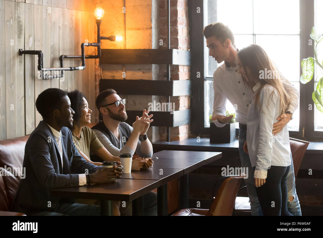 Uomo caucasico introducendo ragazza con gli amici presso il cafe Foto Stock