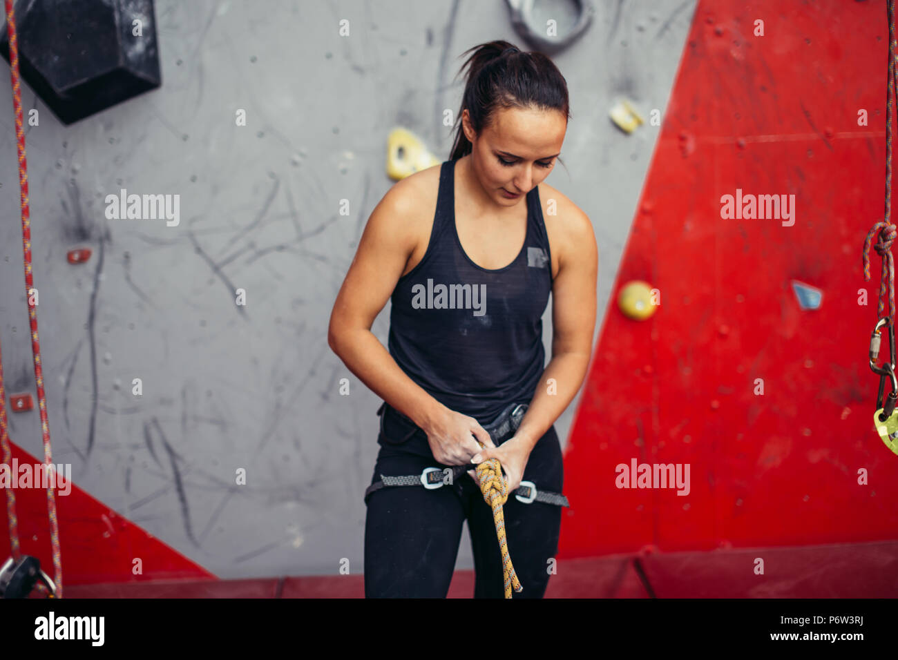 Atletica scalatore femmina nel cablaggio di sicurezza corda di legatura in otto nodi e si prepara a salire. Arrampicata attrezzature Foto Stock