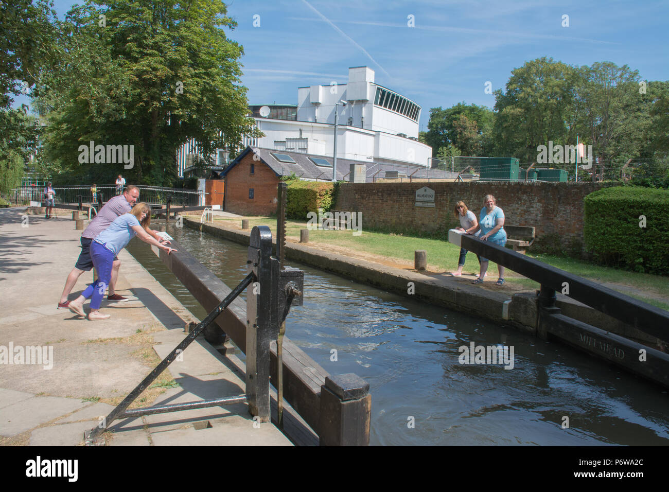 La gente di apertura della serratura porte a Millmead sul fiume Wey a Guildford, Surrey, Regno Unito, con la Yvonne Arnaud theatre in background Foto Stock