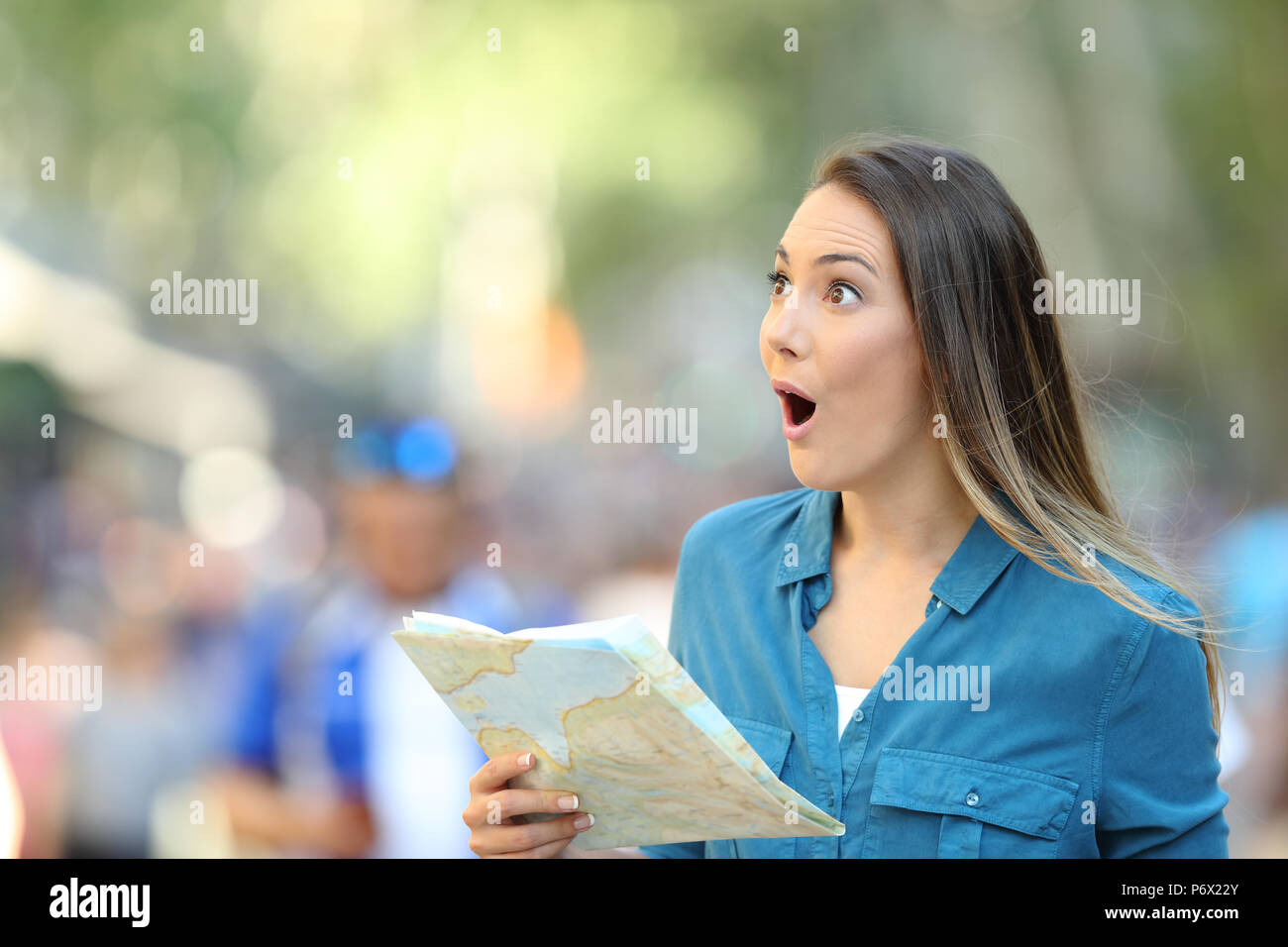 Sorpreso donna sightseeing guardando laterali di contenimento di una mappa su strada Foto Stock