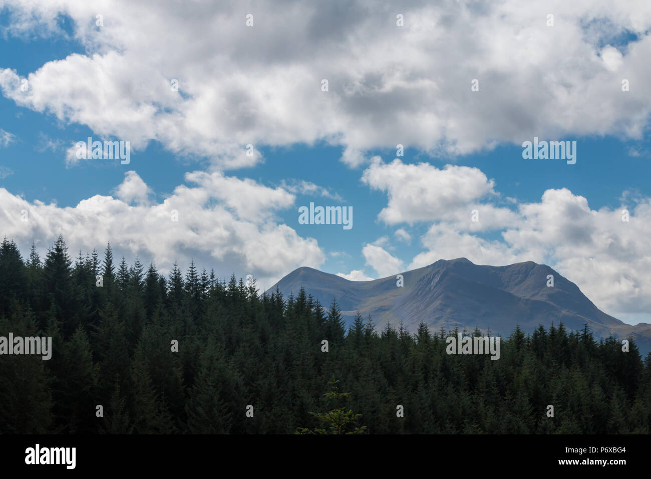 Una catena montuosa sorge su un pinnipo in primo piano, con cielo blu e nuvola che comprende i due terzi superiori dell'immagine. Foto Stock