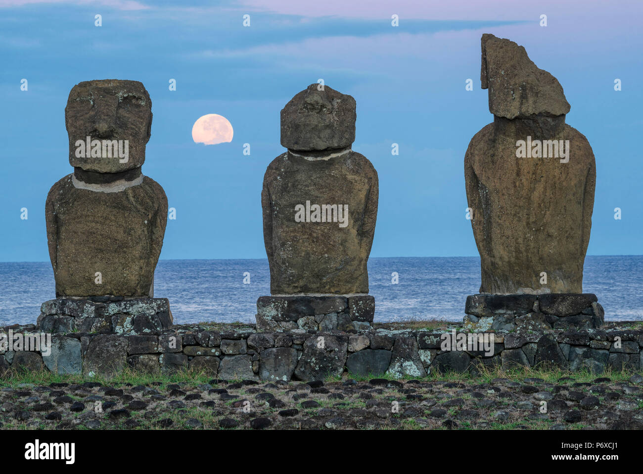 America del Sud, il Cile, l'isola di pasqua, Isla de Pascua, Moai stone figure umane sotto un cielo notturno al sorgere della luna Foto Stock