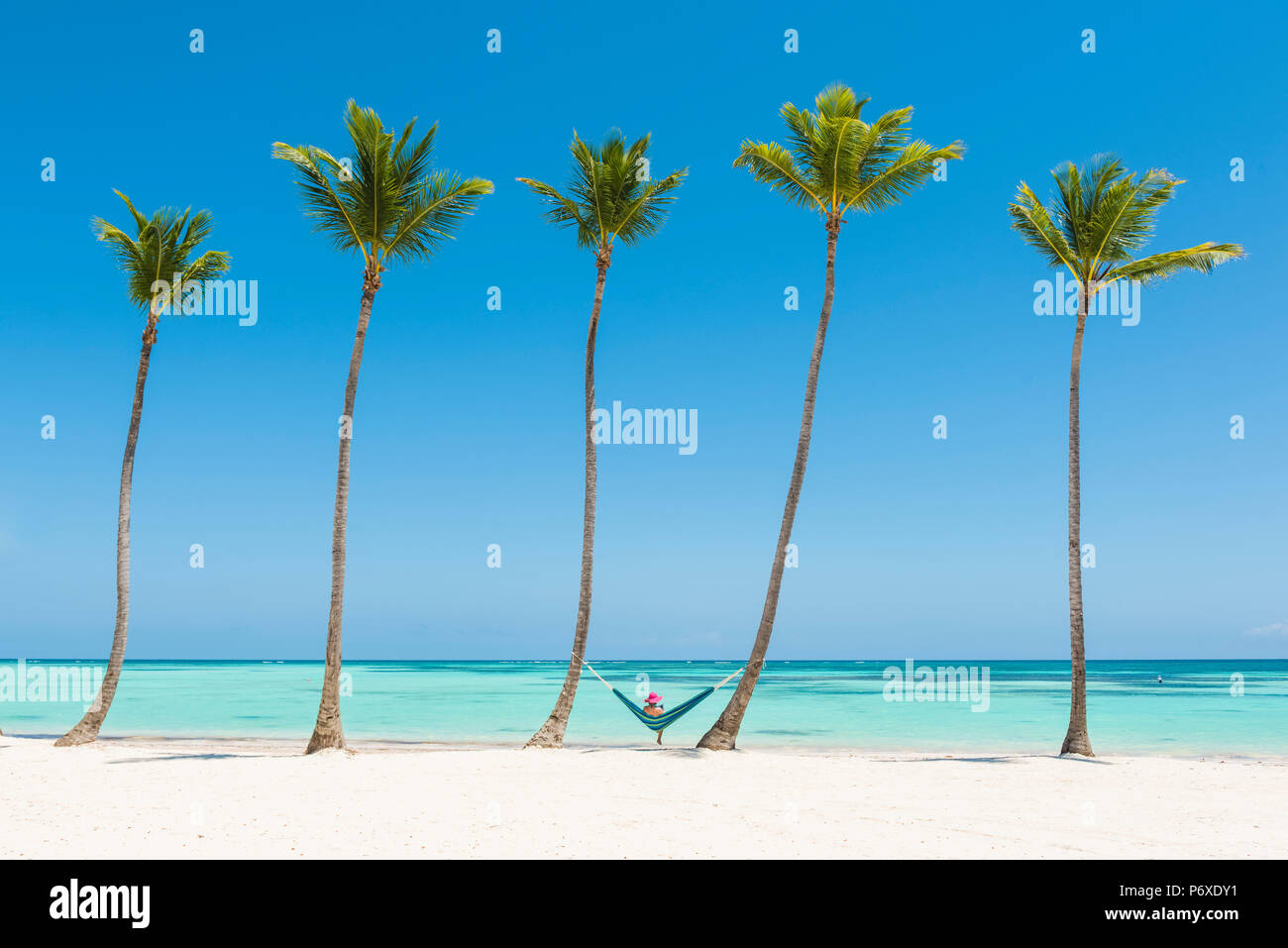 Spiaggia Juanillo (playa Juanillo), Punta Cana, Repubblica Dominicana. Donna relax su una amaca su una spiaggia orlata di palme (MR). Foto Stock