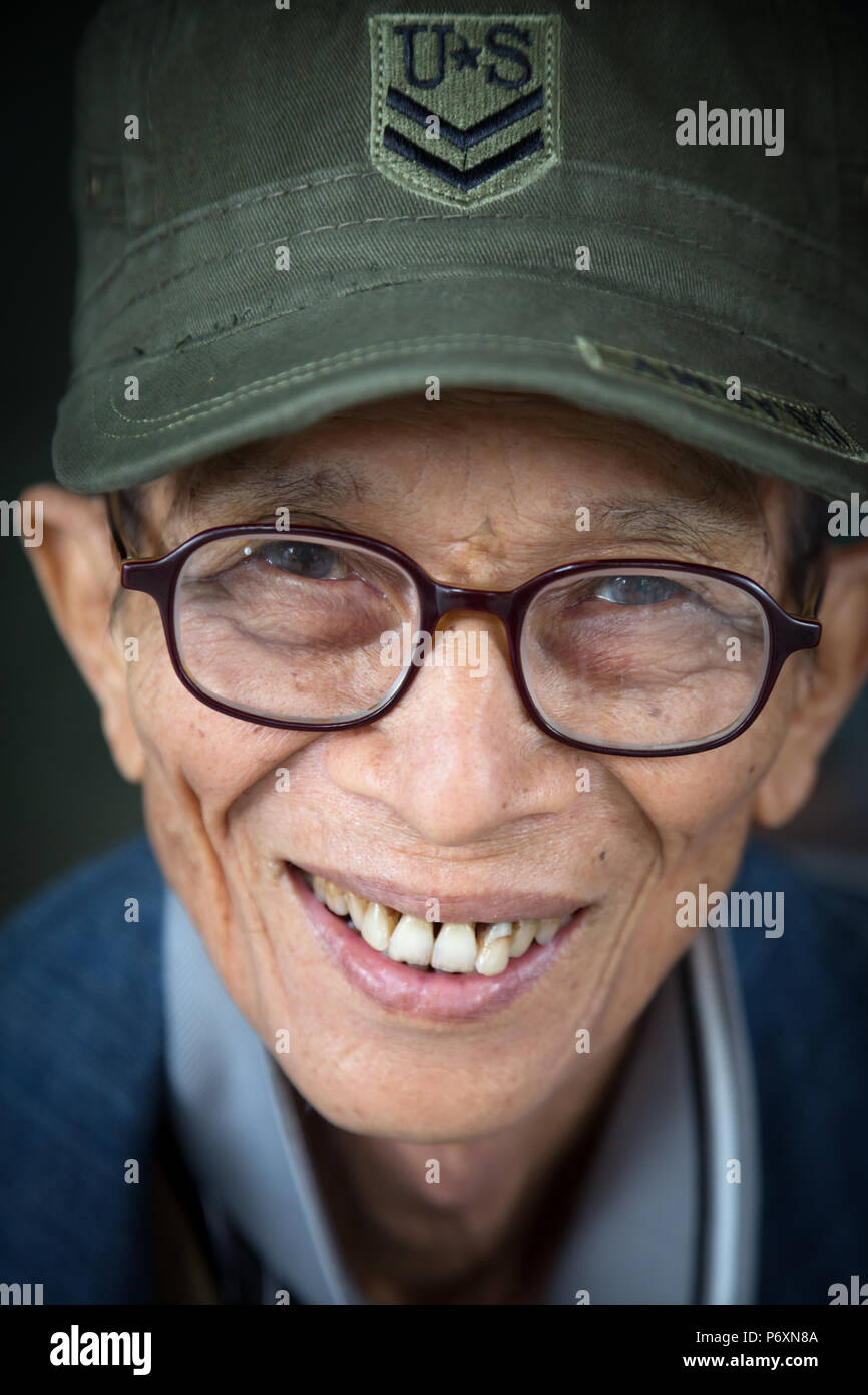 Ritratto di sorridere uomo vecchio con cappuccio Usa a Saigon, Vietnam Foto Stock