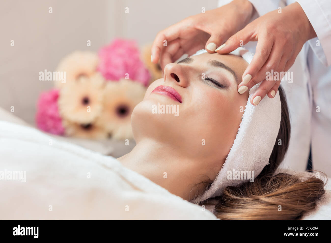 Bella donna rilassante durante il massaggio ringiovanente del viso Foto Stock