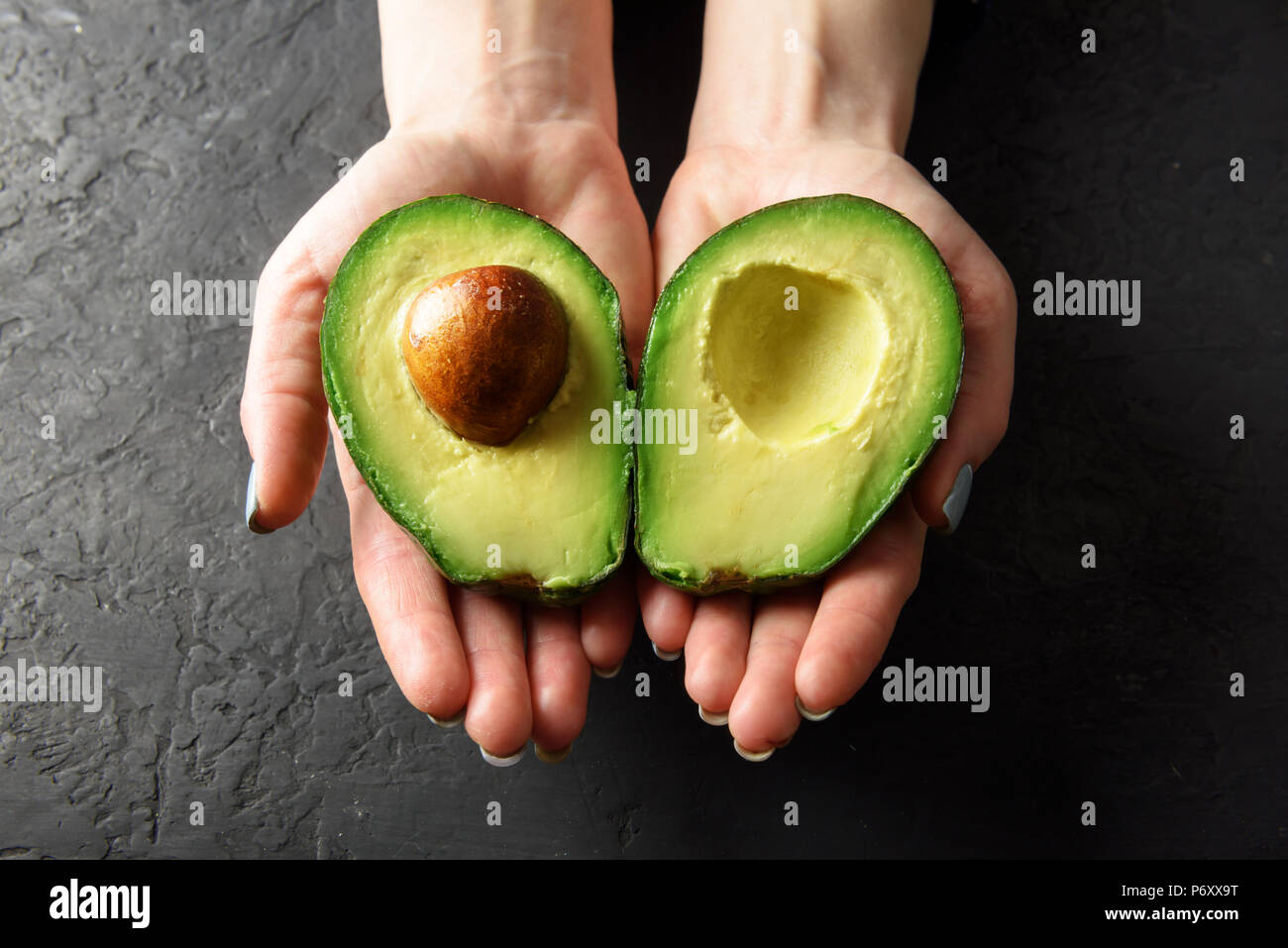 Fresco frutto di Avocado in girl mani Foto Stock