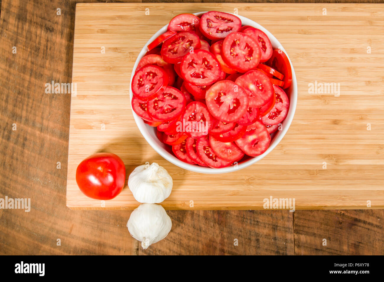 4 spicchi di aglio e una ciotola di rosso dei pomodori a fette Foto Stock