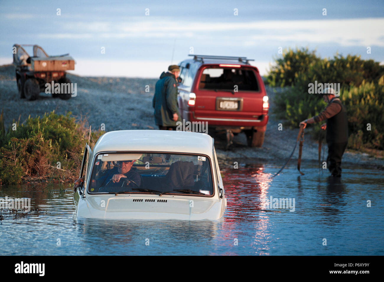 Gli uomini fuori di traino Lada la trazione a quattro ruote motrici il veicolo rimane bloccato nella laguna costiera Foto Stock