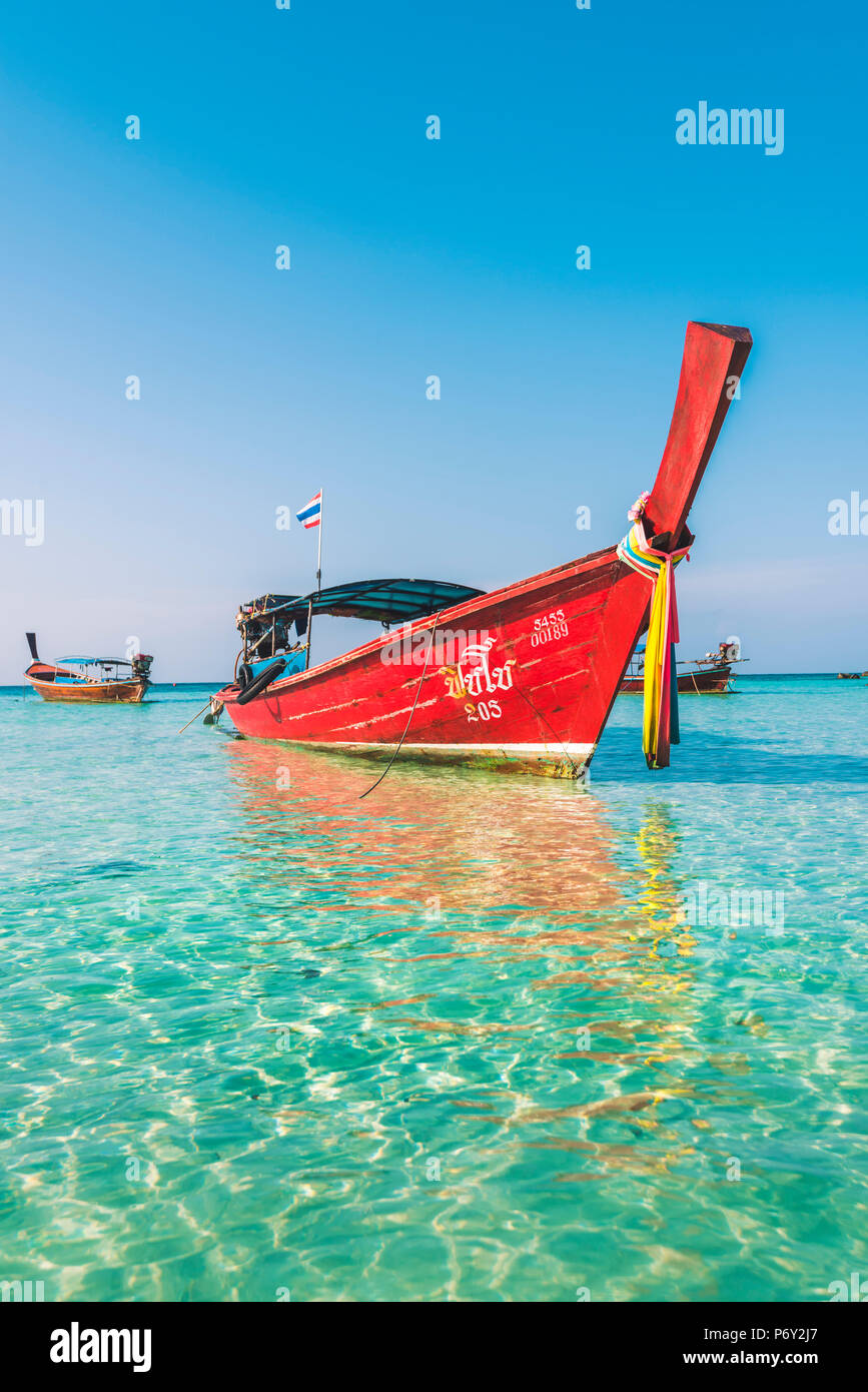Ko Lipe, Provincia di Satun, Thailandia. In legno rosso barca dalla coda lunga sulle acque turchesi. Foto Stock