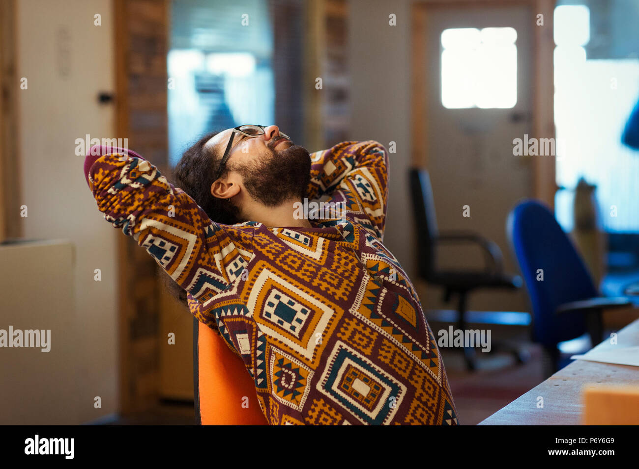 Imprenditore creativo stretching alla scrivania in ufficio Foto Stock