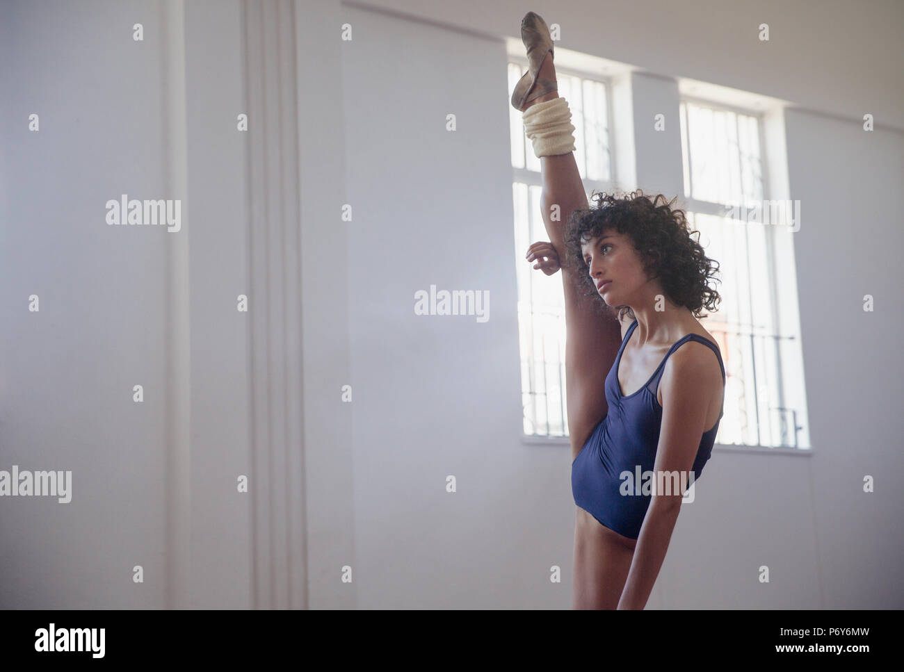 Flessibile femmina giovane ballerino gamba stretching, facendo in piedi si divide in studio di danza Foto Stock