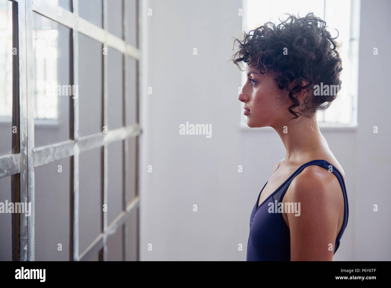 Profilo grave giovane ballerino femmina in piedi in corrispondenza dello specchio in studio di danza Foto Stock