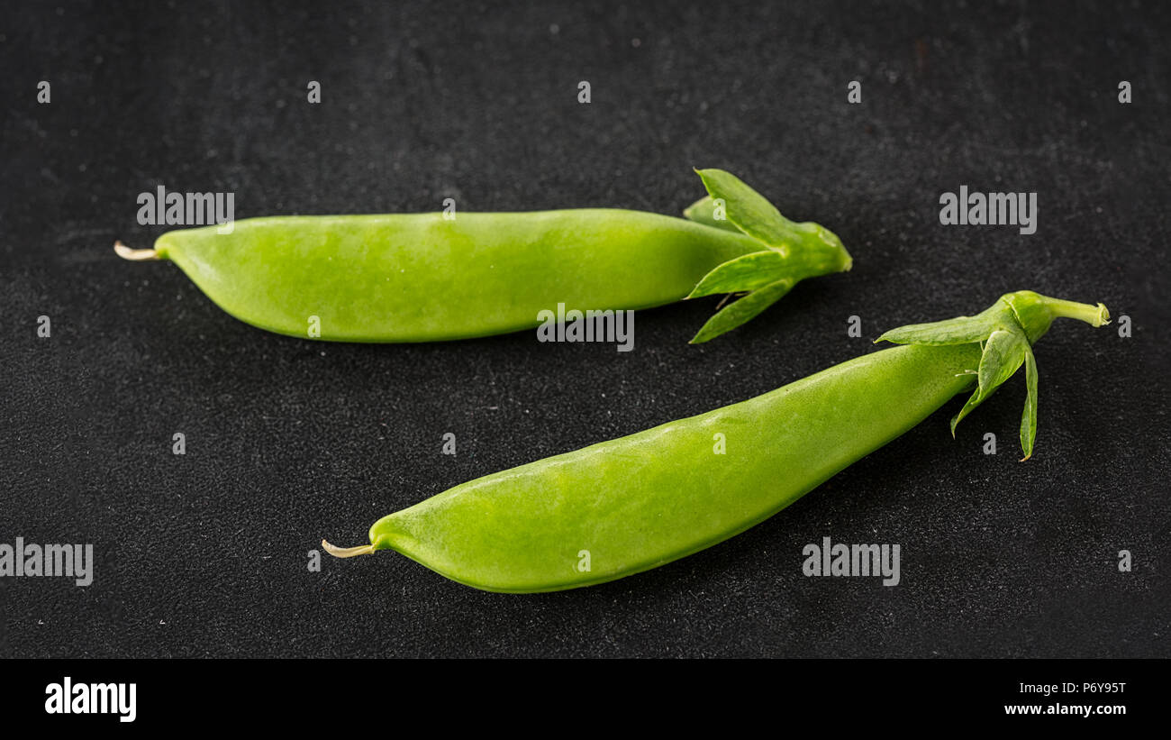 Appena raccolti i piselli della neve su uno sfondo nero. Foto Stock